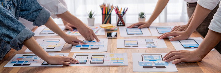 Poster - Panorama shot of front-end developer team brainstorming UI and UX designs for mobile app on paper wireframe interface. User interface development team planning for user-friendly UI design. Scrutinize