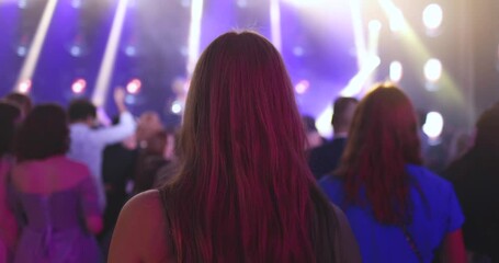 Wall Mural - A crowded concert hall with scene stage lights, audience at a rock show performance with band performing music on a stage, with men and girls dancing on dance floor during a concert festival