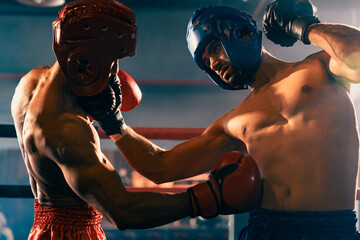 Two athletic and muscular body boxers with safety helmet or boxing head guard face off in fierce boxing match. Boxing fighter competitor fighting in the boxing ring. Impetus