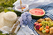 Breakfast picnic with croissants, fruits and flowers on a blanket on a sunny day. Picnic, food, brunch, summer mood.