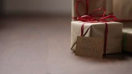 Wall Mural - Slide shot of brown paper gift boxes with red bow on wood table with paper card