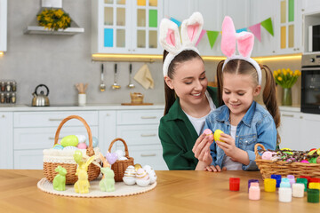 Wall Mural - Mother and her daughter with Easter eggs at table in kitchen