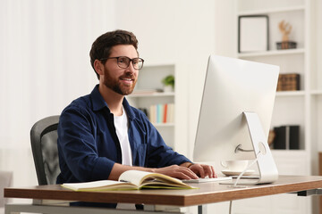 Poster - Home workplace. Happy man working with computer at wooden desk in room