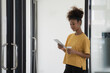 © Songsak C - Image of a young African woman, a company worker in casual wear, smiling and holding a digital tablet.