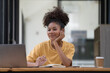 © Songsak C - A beautiful African American girl, student or businesswoman sitting at a desk and writing.