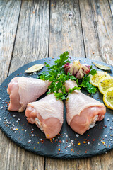 Wall Mural - Raw chicken drumsticks on cutting board with seasonings on wooden table
