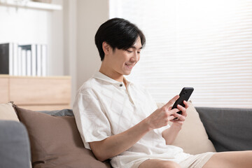 Asian man is smiling on the cellphone like he got a good news. The man seems so happy with the mobile phone screen. Technology make us have a convenience life and also make the world getting smaller.