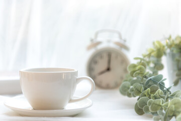 Wall Mural - Select focus.  Coffee morning.  White steaming cup of hot coffee for relax after wake up, vintage alarm clock background. Lifestyle Concept