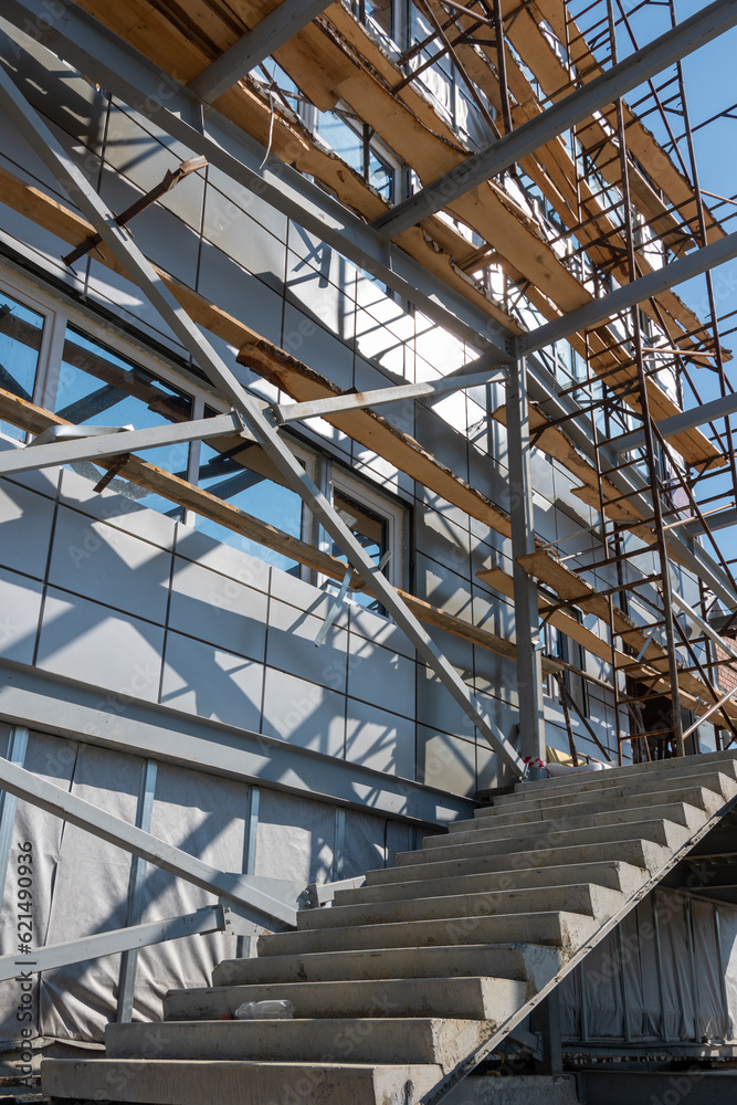 Construction of a building using scaffolding. Facade restoration work. Fragment of scaffolding and stairs