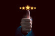 Businessman hand thumb up with glowing yellow five stars for client the best satisfaction evaluation survey after use product and service concept.