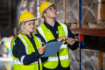 Wall Mural - Male and Female professional worker wearing safety uniform and hard hat inspect product on shelves in warehouse. supervisor worker checklist stock inspecting product in storage for logistic.