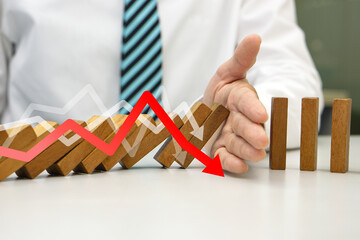 Hand prevent wooden block falling domino effect from continuous fall and virtual arrow pointing down. Risk management, strategic, insurance and business plan concept.