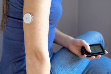 girl sitting with flash glucose monitor, patch on her hand holding monitor
