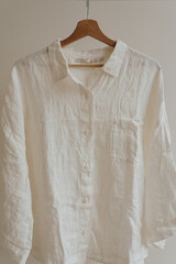 Wall Mural - Wrinkled white female blouse, shirt on hanger. Minimalist essential fashion clothes