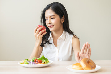 Diet, dieting, happy asian young woman, girl hand push out, deny sweet donut, doughnut on plate, choose red apple and green vegetable salad, eat food for good healthy, female getting weight loss.