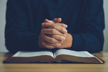 Canvas Print - Man hands praying to god on the open bible on a wooden table. begging for forgiveness and believing in goodness. Pray for god blessing to wish to have a better life and life to be out of the crisis