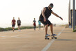 © KONSTANTIN SHISHKIN - Adult attractive man in black clothes skating on the street by the beach