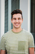 © Jose Calsina - Vertical portrait of handsome confident young man with toothy perfect white smile looking at camera at university campus. Cheerful teenage male posing succesful in casual stylish look otudoors. High