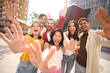 © CarlosBarquero - Cheerful multicultural group of friends waving happy looking at camera. Portrait of excited cheerful young people showing hands for funny photo. People enjoying leisure time outdoors together.