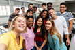 © Xavier Lorenzo - Diverse group of young student people taking selfie at university classroom. Millennial classmates posing with male teacher for self photo together. Education and community concept.