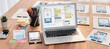 © InfiniteFlow - Digital and paper wireframe designs for web or mobile app UI UX display on laptop computer screen. Panoramic shot of developer workspace for brainstorming and design application framework. Scrutinize