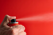 Man spraying repellent on red background