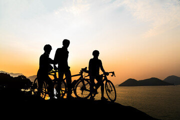 A silhouette of a cyclist on a mountain bike riding in a dramatic sunset