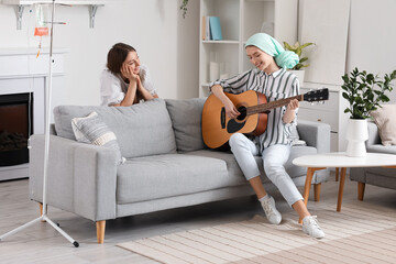 Sticker - Teenage girl after chemotherapy playing guitar with her sister at home