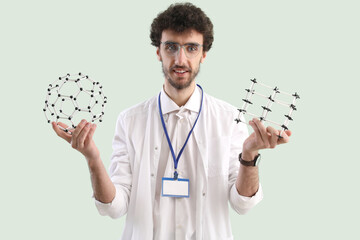 Canvas Print - Male student with molecular models on green background