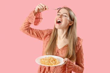 Wall Mural - Young woman eating tasty pasta on pink background