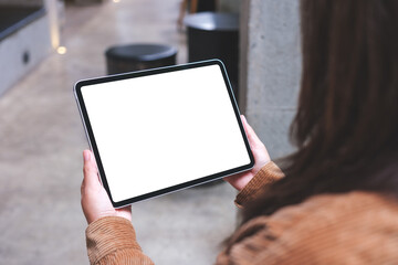 Mockup image of a woman holding digital tablet with blank white desktop screen in cafe