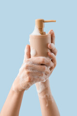 Wall Mural - Hands with liquid soap on light blue background