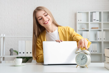 Wall Mural - Young businesswoman with laptop and alarm clock in office