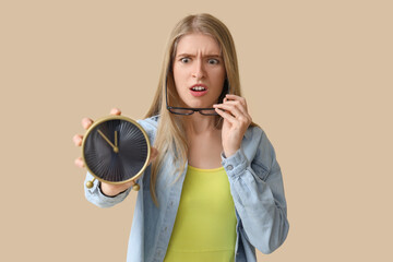 Wall Mural - Stressed young woman with alarm clock on beige background. Deadline concept