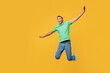 © ViDi Studio - Full body young man of African American ethnicity he wears casual clothes green t-shirt hat jump high with outstretched hands pov flying isolated on plain yellow background studio. Lifestyle concept.