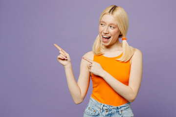 Wall Mural - Young blonde woman she wear orange tank shirt casual clothes point index finger aside indicate on workspace area copy space mock up isolated on plain pastel light purple background. Lifestyle concept.