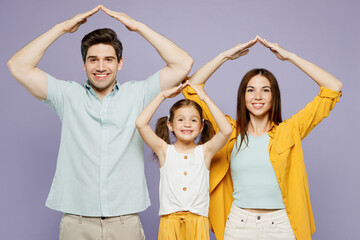 Young happy smiling fun parents mom dad with child kid daughter girl 6 years old wears blue yellow casual clothes hold hands above head pov roof isolated on plain purple background Family day concept