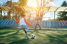Father And Son Play Football On Stadium Outdoors, Happy Family Bonding, Fun, Players In Soccer In Dynamic Action Playing In Sunny Day, Holidays Time.
