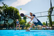 © Drazen - Paddle tennis player making an effort to while hitting ball during match on outdoor court.
