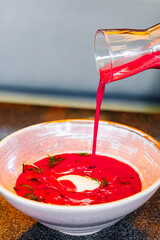 Poster - waiter pours cold beetroot soup into plate