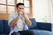 © offsuperphoto - young man having a cold, using tissue paper and blowing his nose on sofa
