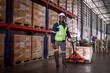 © APchanel - Warehouse workers working factory cargo hand pulling pallet truck, stack cardboard boxes on wooden pallet is cargo shipment import export transportation concept.