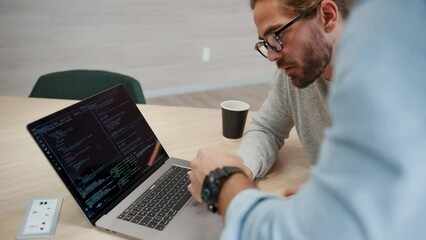 Business men having a discussion in an office, sharing ideas for a software design project. Two computer programmers working together on a developing a code, they review their progress using a laptop.