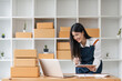© Natee Meepian - Asian woman online store business owner, online shop owner working from home, products for sale on and accepting orders and packing products for customers with courier service