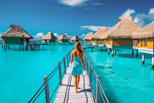 Luxury Over Water Bungalows. Tahiti Resort Woman Walking On Wooden Pier And Clear Blue Water. Generative AI
