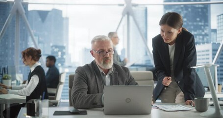 Poster - Senior Male Financial Analyst And Female Project Manager Working With Laptop Computer In Modern Downtown Office. Caucasian Man And Woman Looking For Investment Opportunities In Banking or Tech Sectors