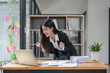 © Natee Meepian - Happy young Asian business woman celebrating success at work in office looking at laptop excited about financial trading growth, goals achievement good online results