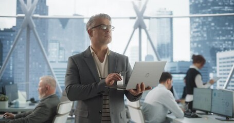 Poster - Succeful Caucasian Businessman Walking In Modern Office With Diverse Employees In Downtown Skyscraper. Middle Aged Male Entreprenuer Using Laptop Computer In E-commerce Company Workspace.