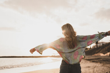 One happy beautiful woman walking on the sand of the beach enjoying and having fun at the sunset of the day. Leisure time on vacations, freedom concept.