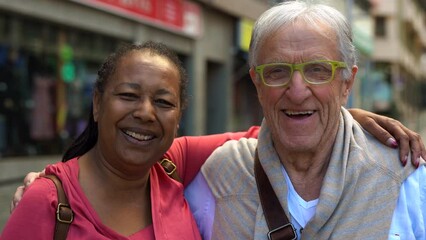 Wall Mural - Multiracial senior couple smiling in front of camera while waiting at the tram station in the city
